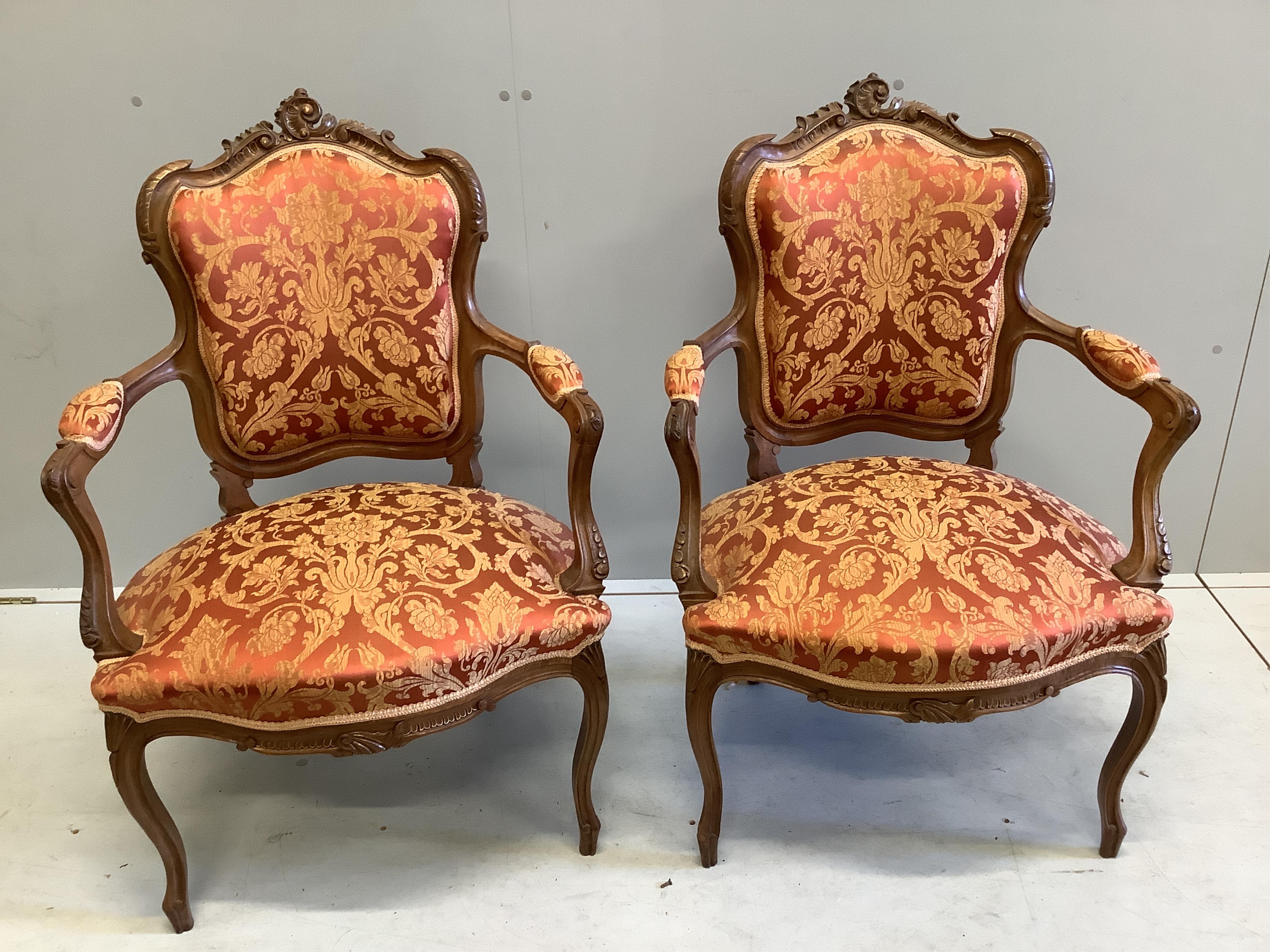 A pair of early 20th century French walnut upholstered open armchairs, width 63cm, depth 53cm, height 94cm